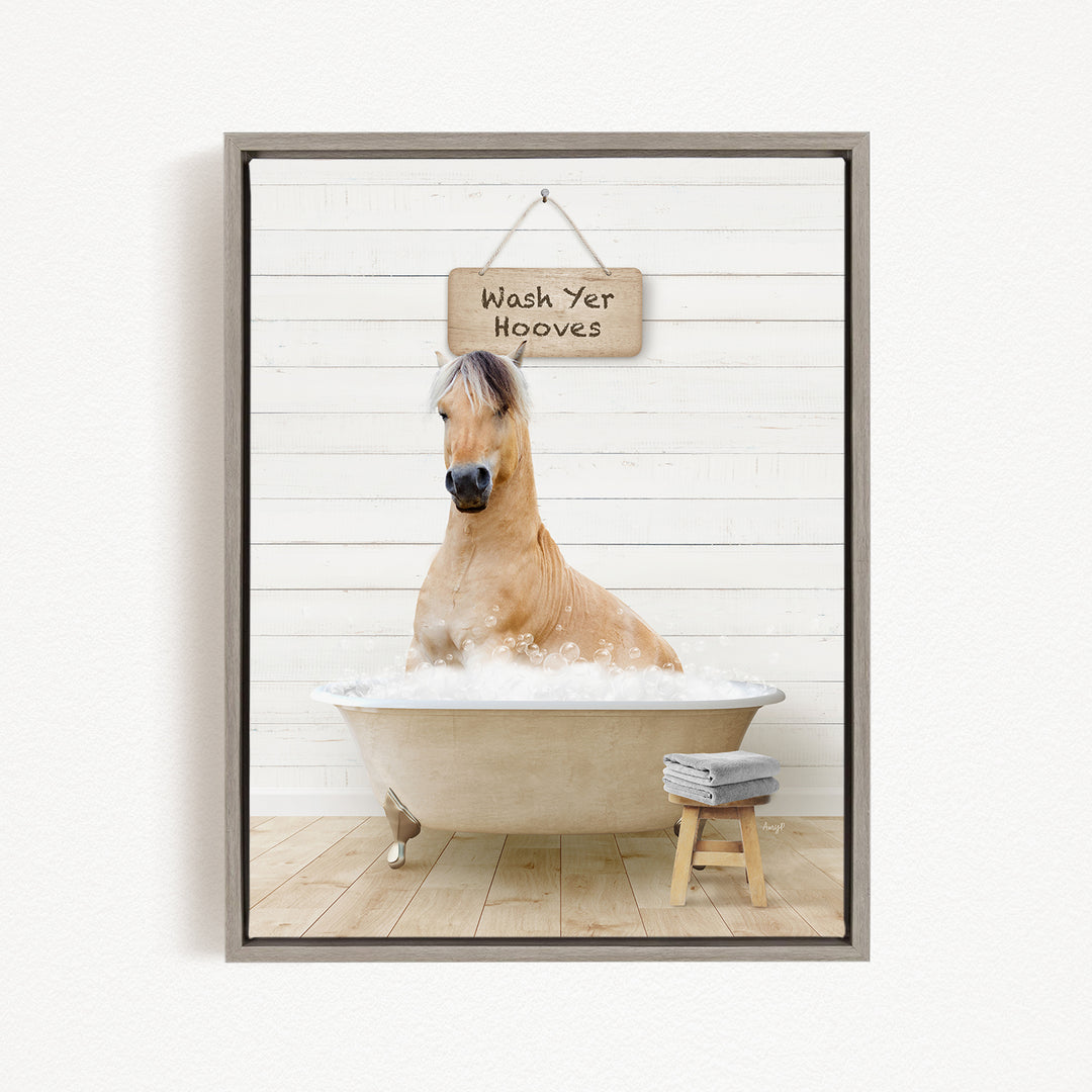 A light brown horse is sitting in a bathtub filled with water, with a sign above it that says "Wash Your Hooves".