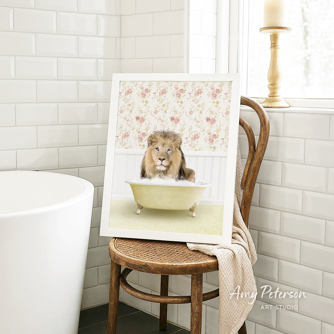 A framed image of a lion sitting in a bathtub, surrounded by a floral pattern, is displayed on a wooden chair in a bathroom setting.