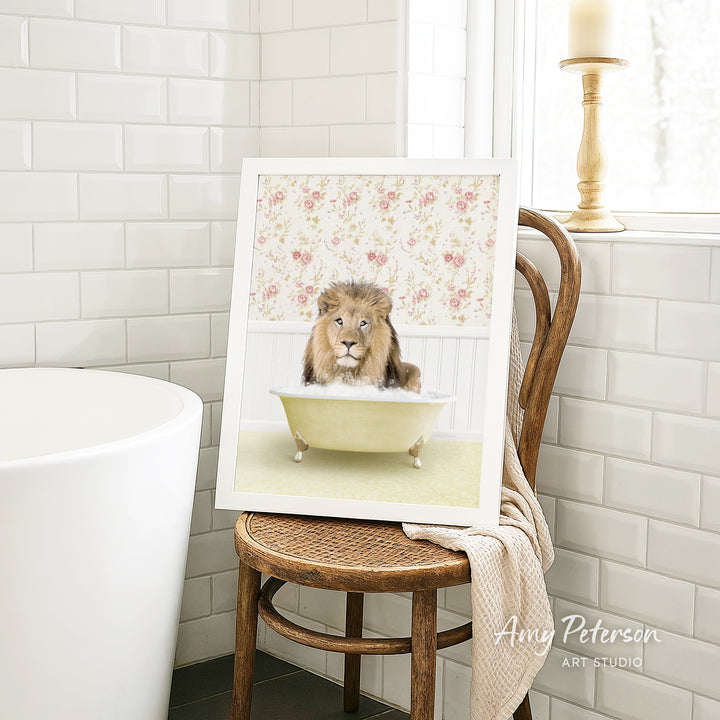 A framed image of a lion sitting in a bathtub, surrounded by a floral pattern, is displayed on a wooden chair in a bathroom setting.