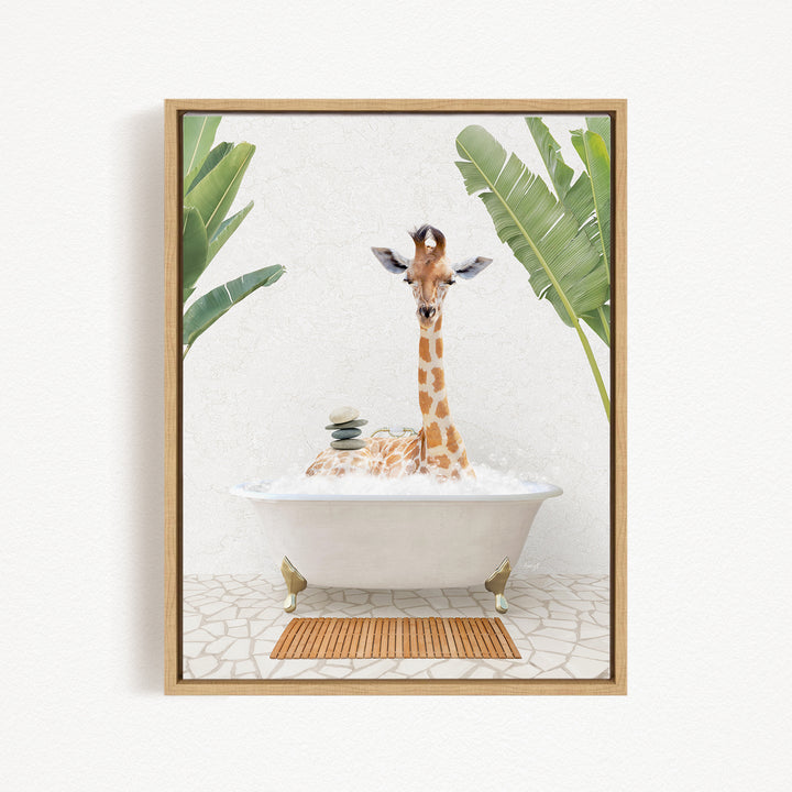 A giraffe sitting in a white bathtub filled with bubbles, surrounded by green leaves and a wooden mat on the floor.
