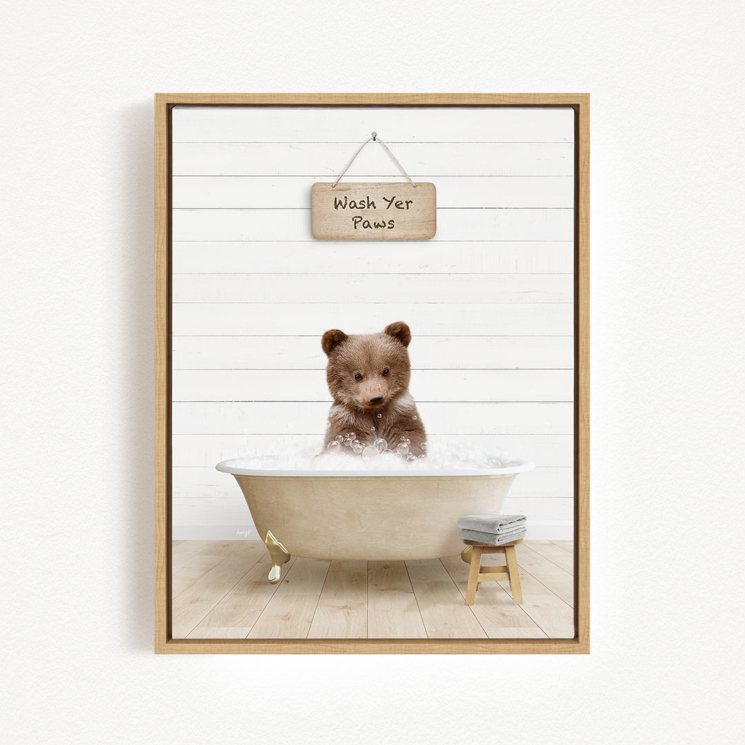 A cute brown bear sitting in a bathtub filled with bubbles, with a sign above that says "Wash Your Paws".
