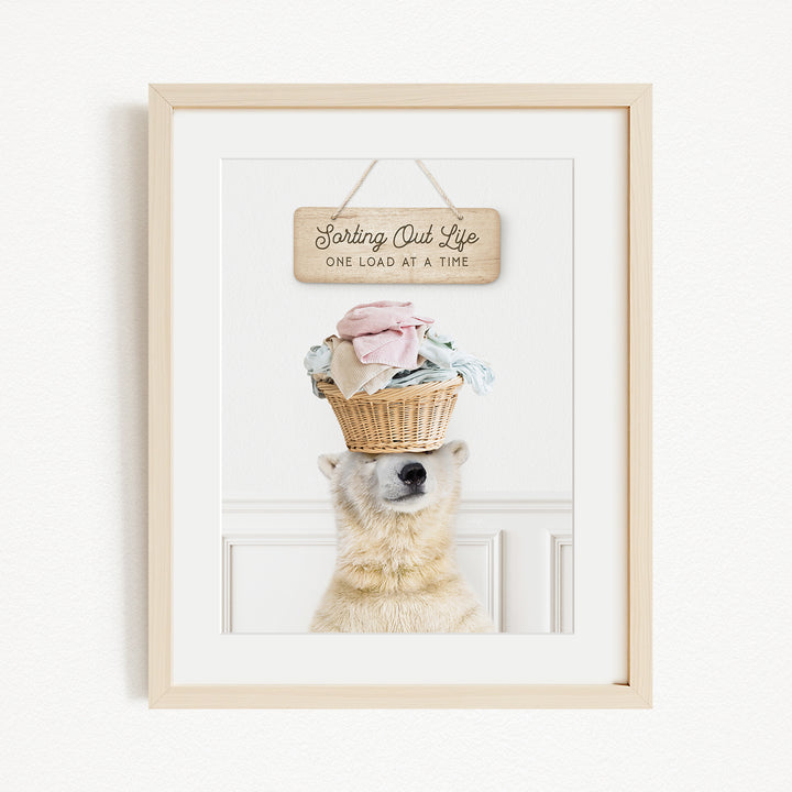 A polar bear balancing a basket of laundry on its head, with a wooden sign above that reads "Sorting Out Life One Load at a Time".