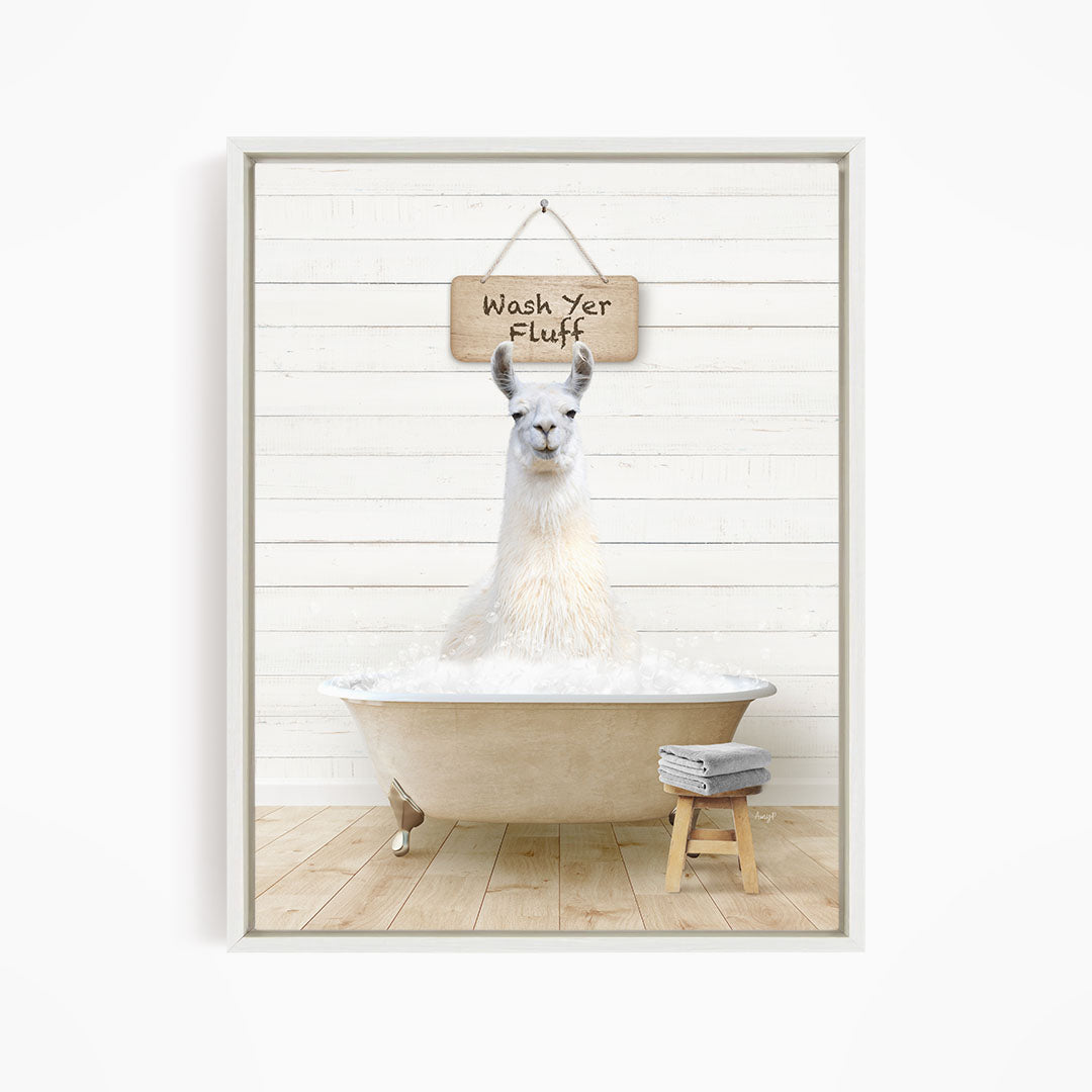 A white llama sitting in a bathtub, with a wooden sign above it that says "Wash Yer Fluff".