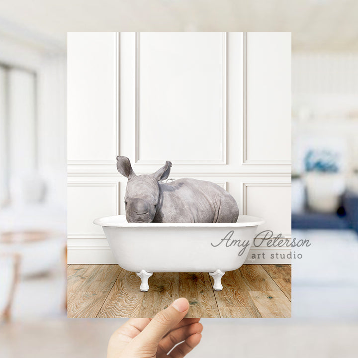 a hand holding a photo of a rhino in a bathtub