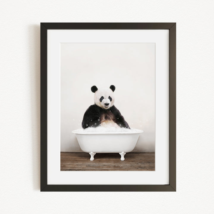 A panda bear sitting in a white bathtub filled with bubbles, looking directly at the camera.
