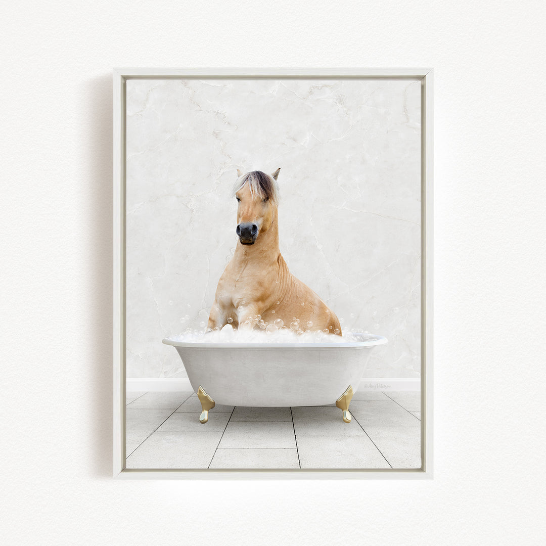 A light brown horse is sitting in a white bathtub filled with bubbles, creating a whimsical and playful scene.