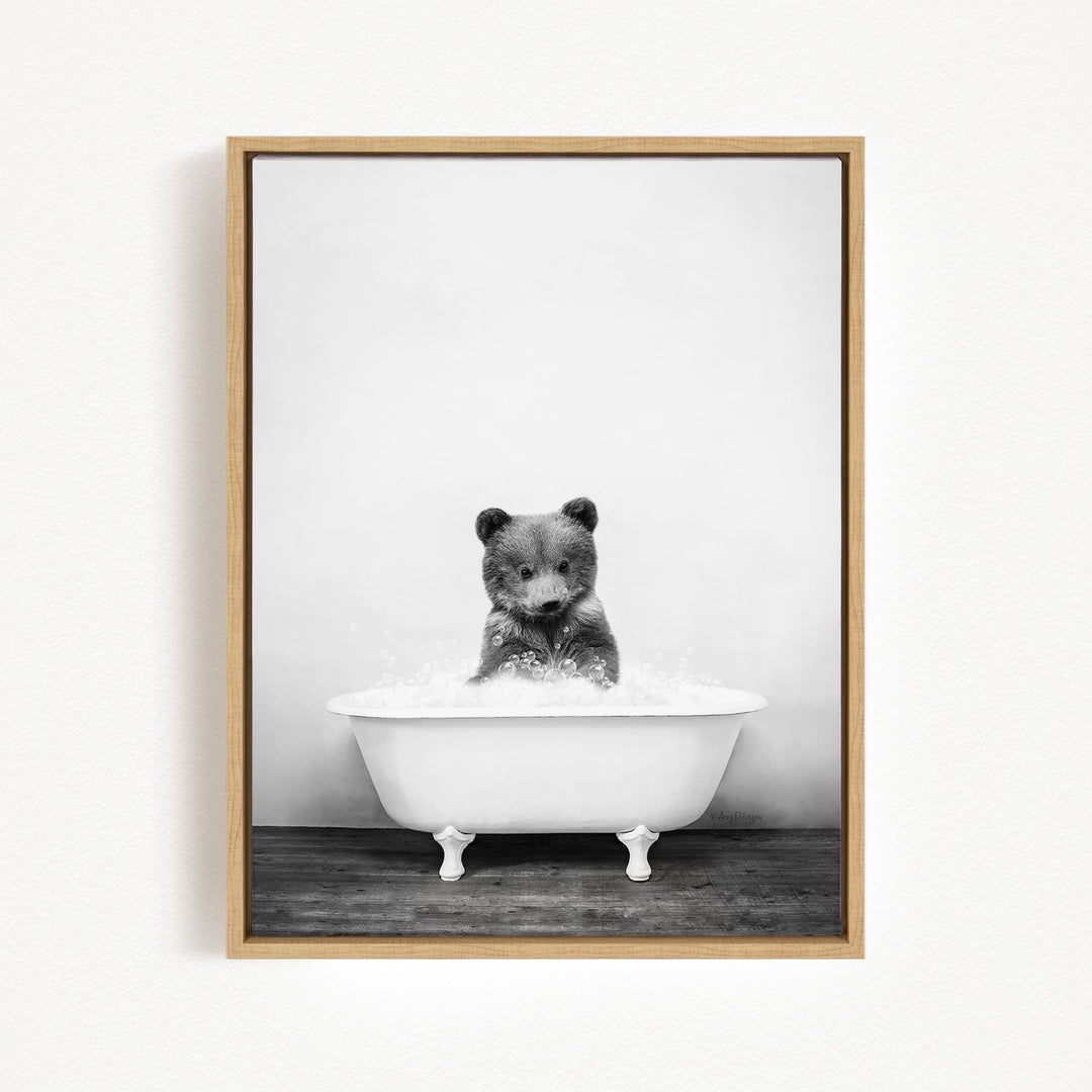 A black and white photograph of a bear sitting in a bathtub filled with water.