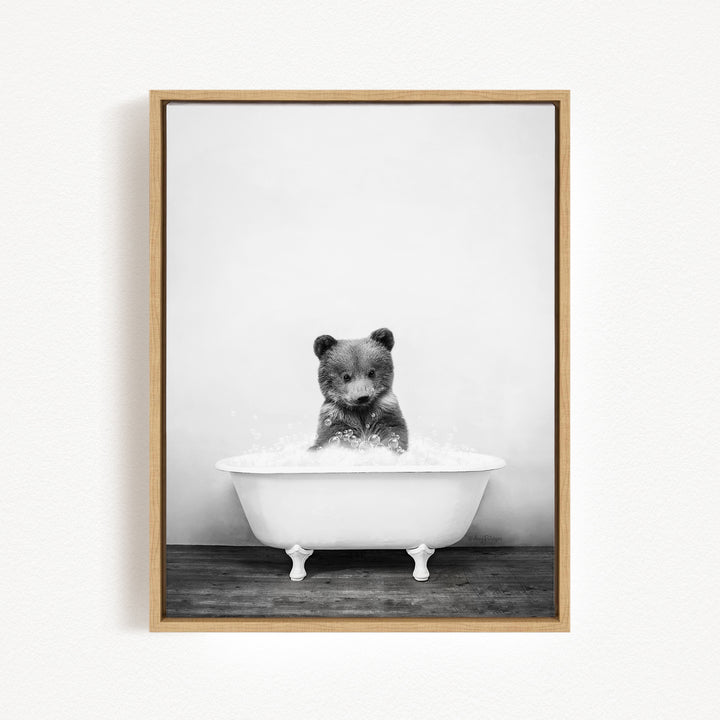A black and white photograph of a bear sitting in a bathtub filled with water.