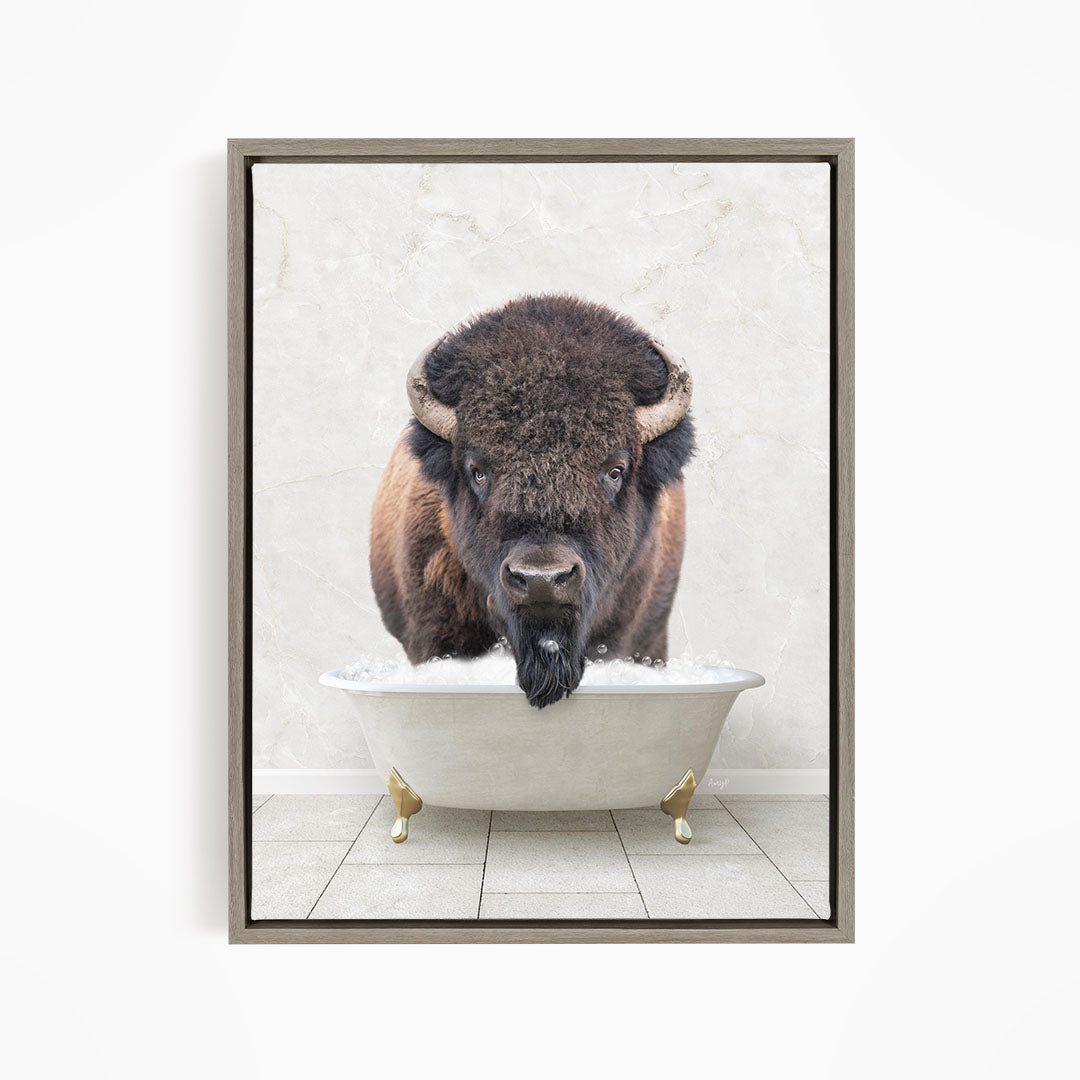 A buffalo with large horns is standing in a white bathtub, appearing to be enjoying a bath.