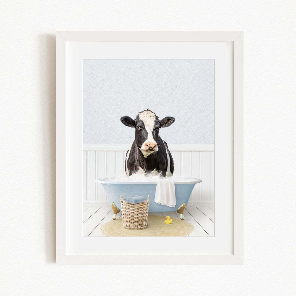 A black and white cow is sitting in a blue bathtub filled with water, surrounded by rubber ducks and a basket.