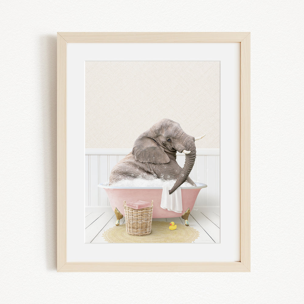A gray elephant is sitting in a pink bathtub filled with bubbles, surrounded by a yellow rubber duck and a basket.