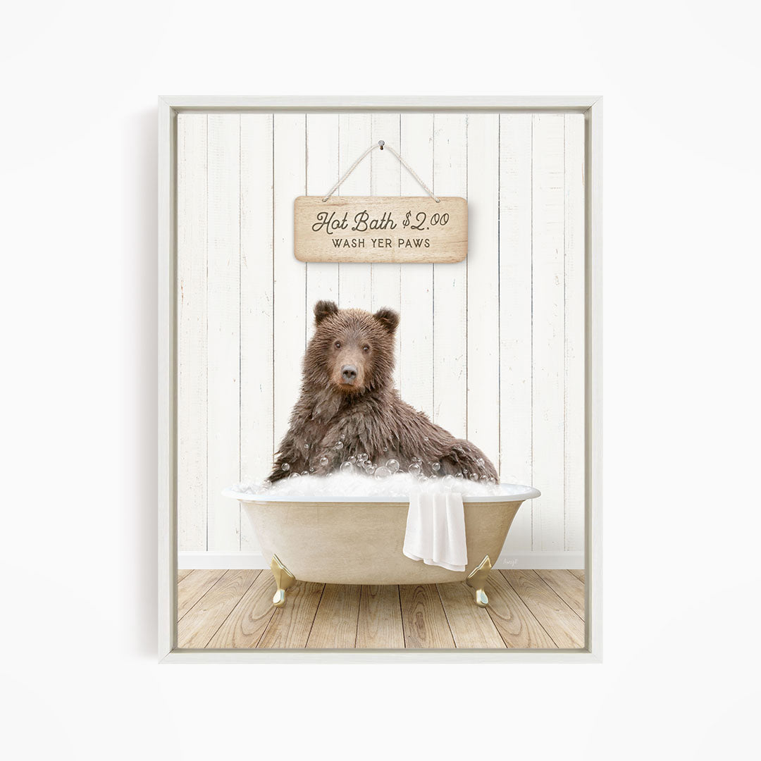 A brown bear sitting in a bathtub filled with water, with a sign above the bear that reads "Hot Bath $2.00 WASH YOUR Paws".