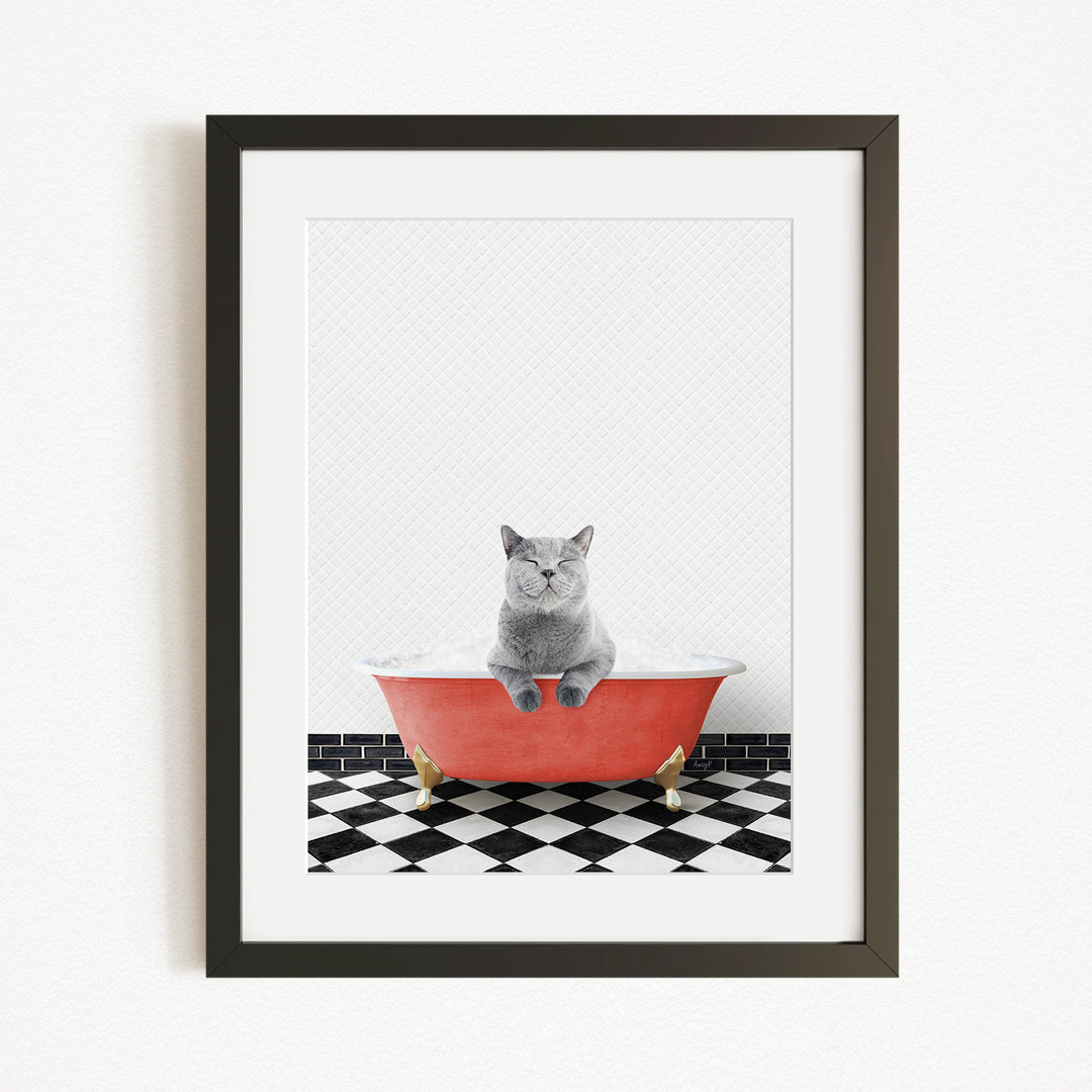 A gray cat sitting in a red bathtub on a black and white checkered floor.