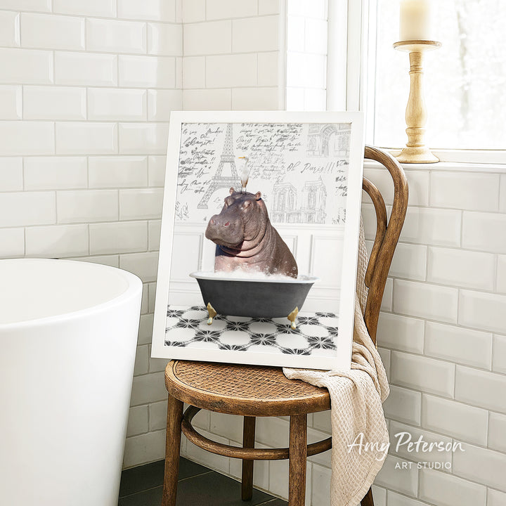 A framed image of a hippopotamus sitting in a bathtub, surrounded by a tiled pattern, is displayed on a wooden chair in a bathroom setting.
