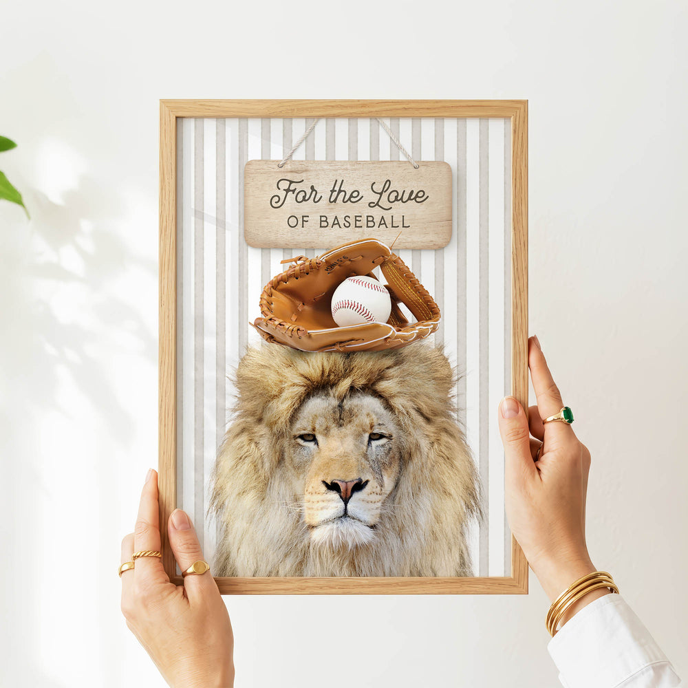 A person's hands are holding a framed picture of a lion with a baseball glove on its head, and a sign above the picture says "For the Love of Baseball".