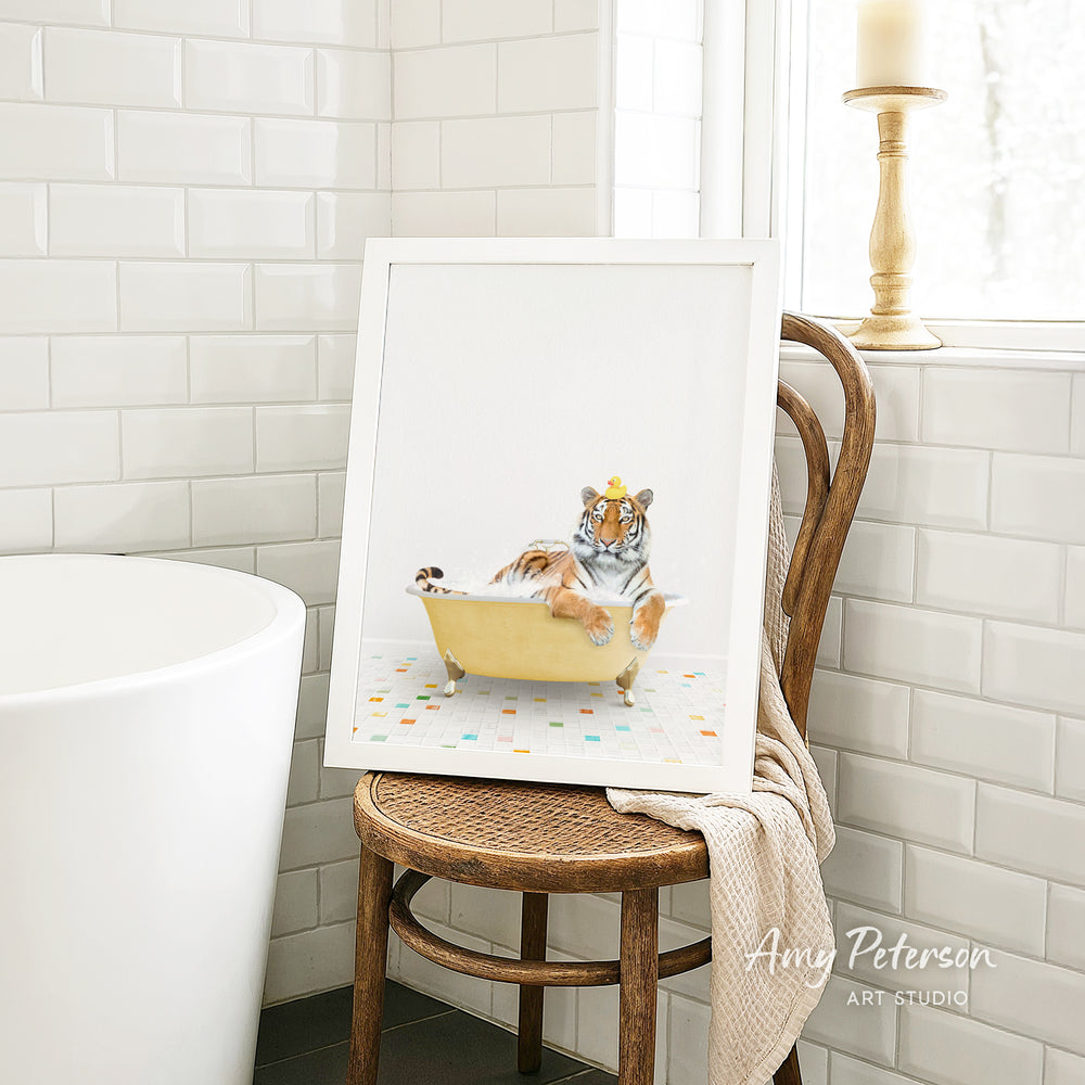 A framed image of a tiger sitting in a bathtub, surrounded by colorful tiles, is displayed on a wooden chair in a bathroom setting.