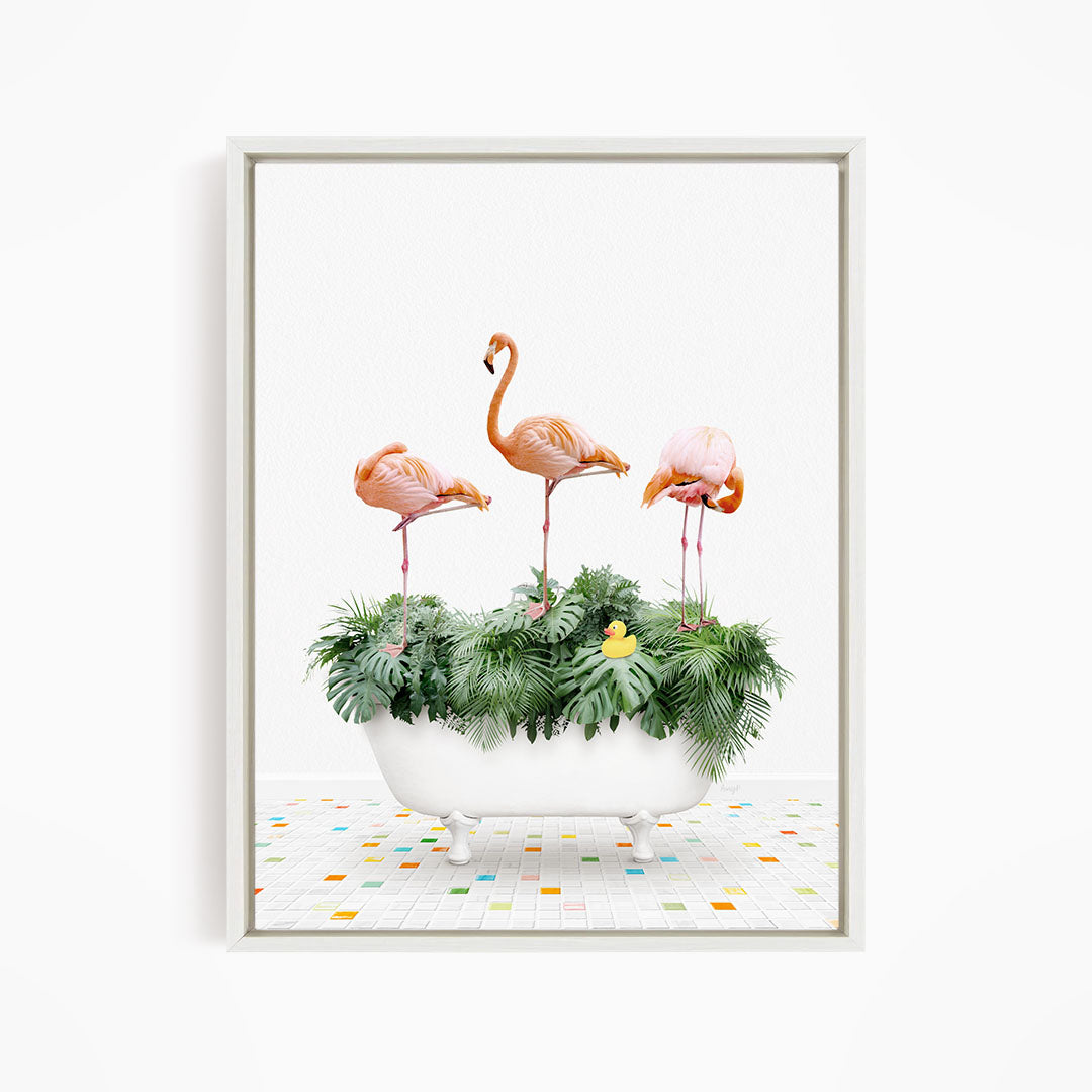 A framed image depicting three flamingos standing in a white bathtub filled with green plants and a yellow rubber duck.