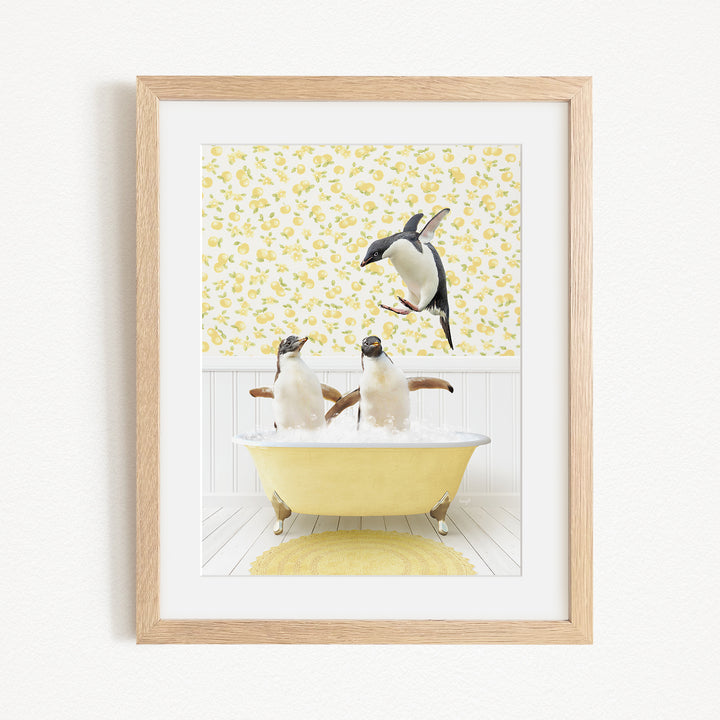 A framed image depicting two penguins sitting in a yellow bathtub, with one penguin standing on the edge of the tub and another penguin sitting inside the tub.