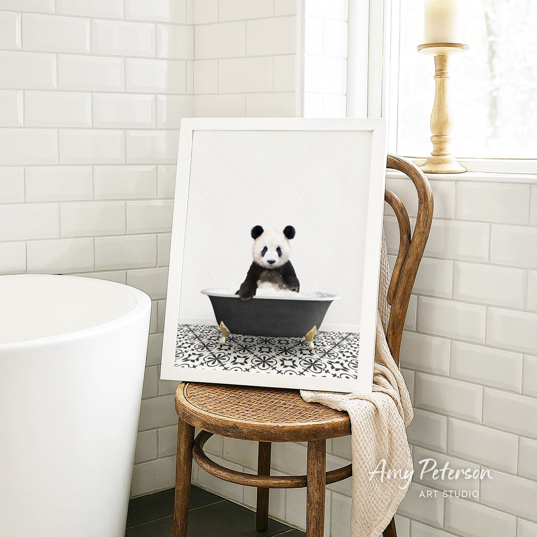 A framed image of a panda sitting in a bathtub is displayed on a wooden chair in a bathroom setting.