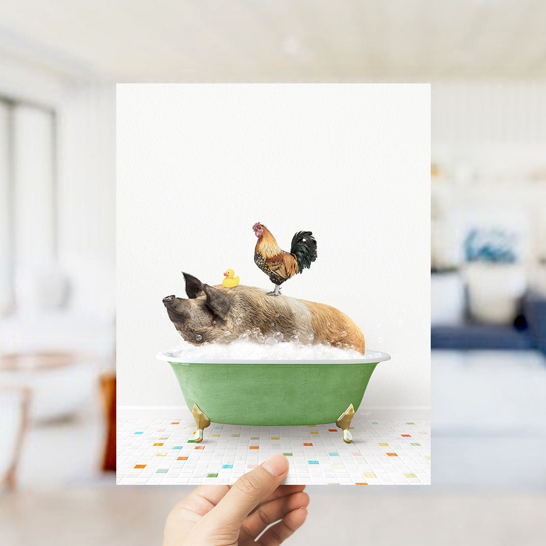 A hand holds up a framed image depicting a pig sitting in a green bathtub, with a rooster perched on its back.