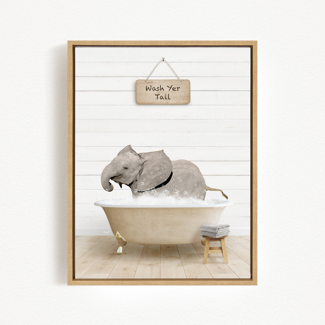 A framed image depicting a gray elephant sitting in a bathtub, with a sign above that says "Wash Your Tail".