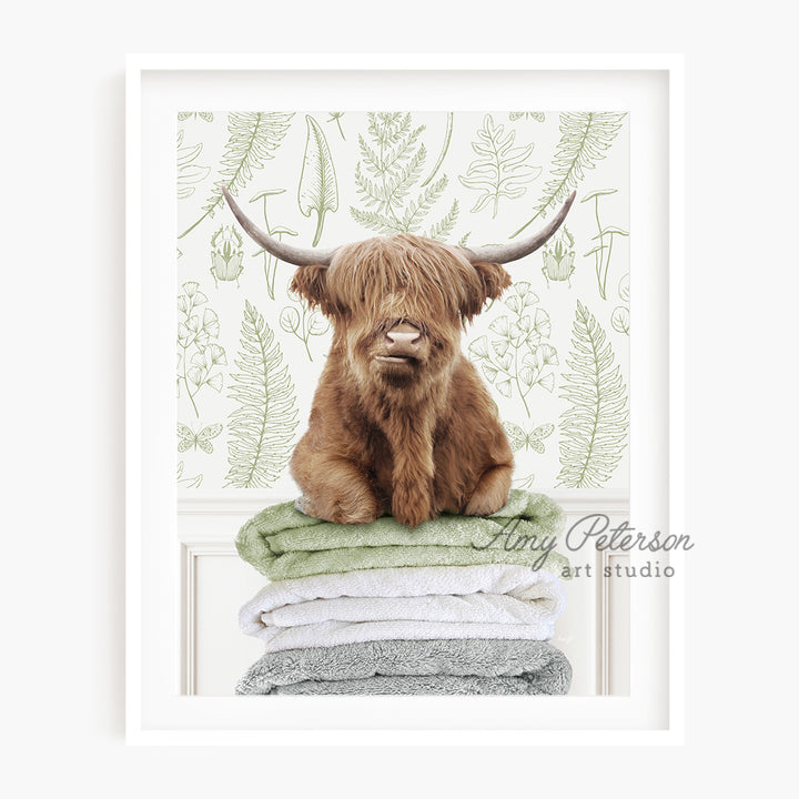 a picture of a highland cow sitting on a stack of towels