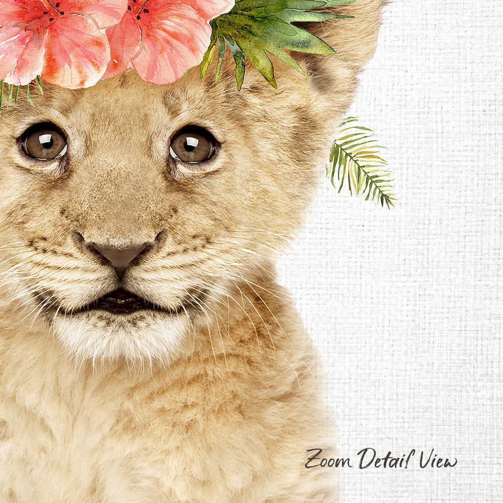 A close-up portrait of a young lion cub with a floral headpiece on its head, set against a white background.