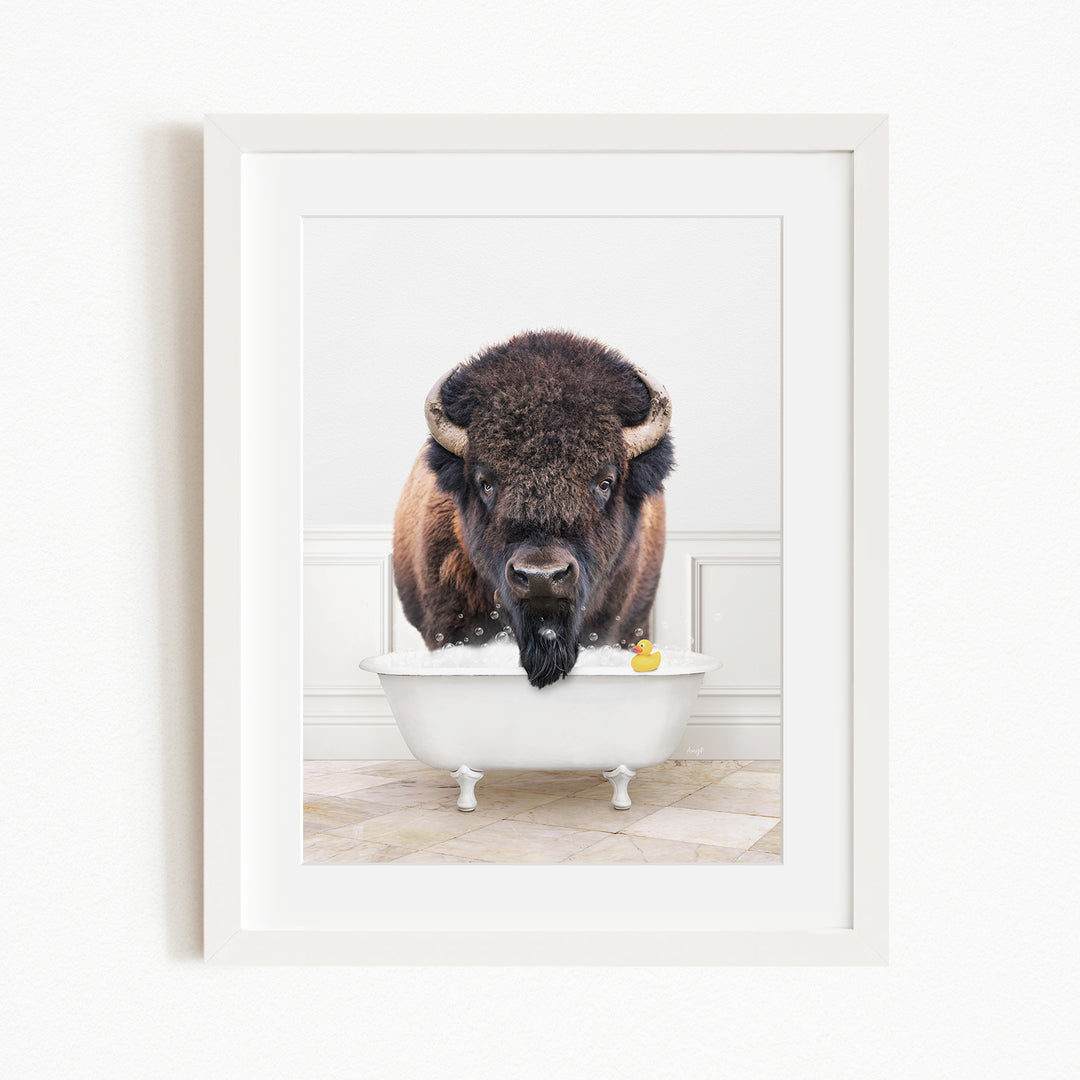 A buffalo with large horns is standing in a white bathtub, with a yellow rubber duck floating in the water.