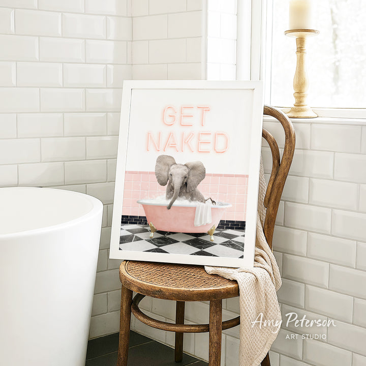 A framed image of an elephant sitting in a pink bathtub, with the text "GET NAKED" displayed on the frame.