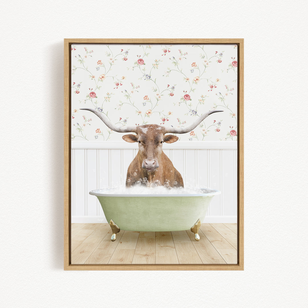 A brown steer with large horns is sitting in a green bathtub filled with bubbles, with a floral wallpaper in the background.