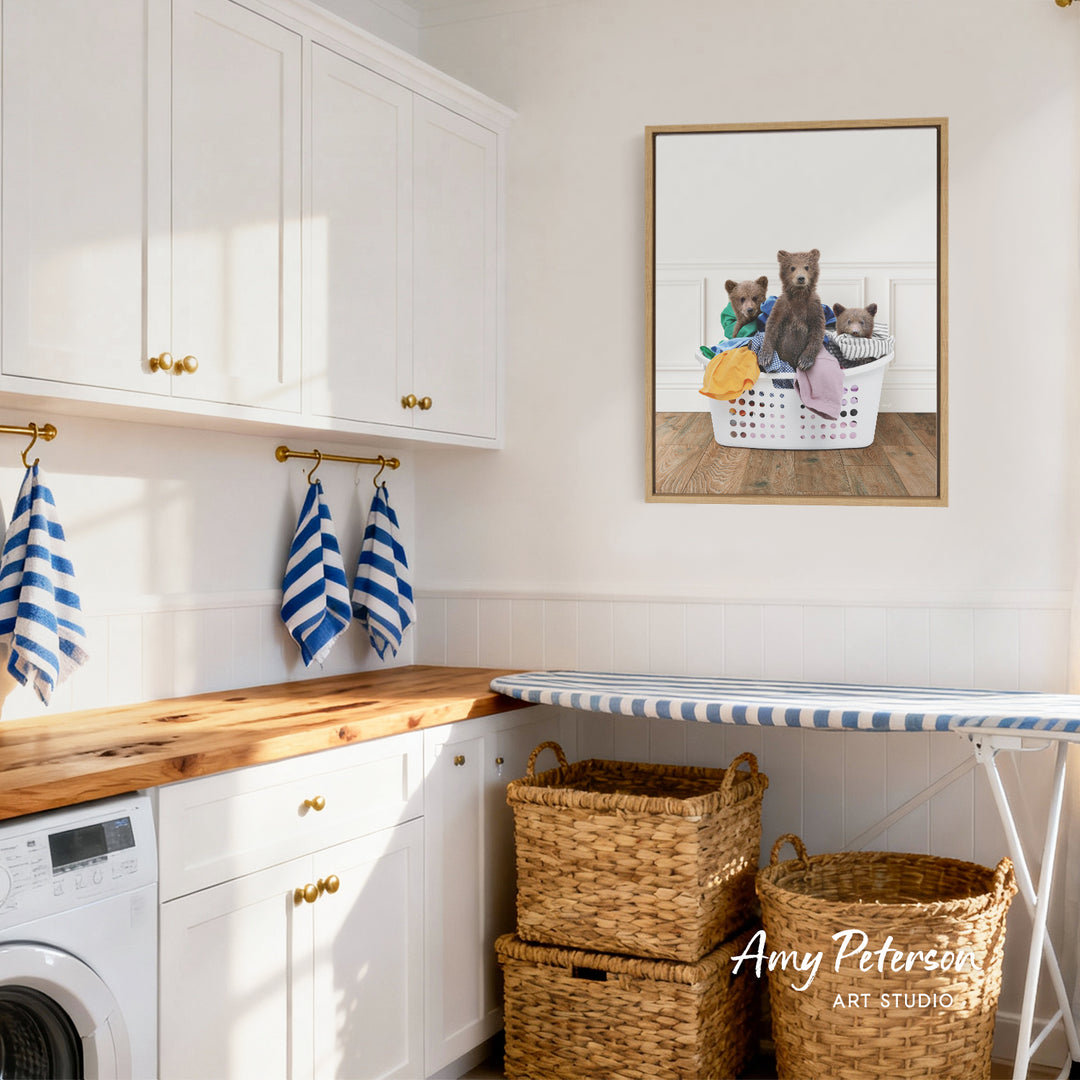 A cozy laundry room with white cabinets, a wooden countertop, and a framed image of three bears sitting in a laundry basket.