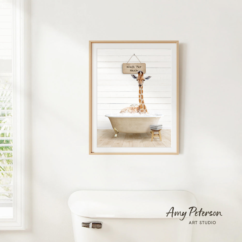 A framed print of a giraffe sitting in a bathtub, with a sign above it that says "Wash Your Giraffe".