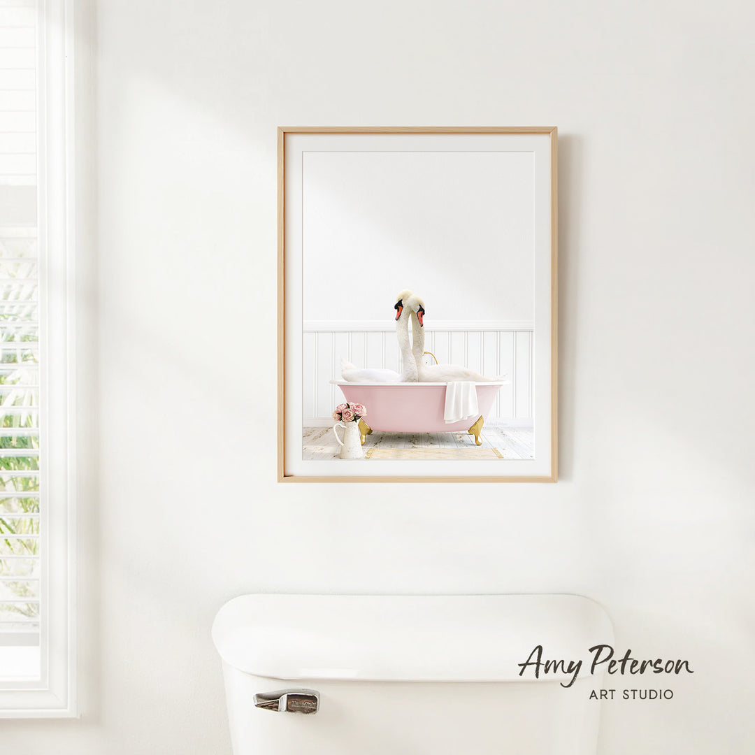 A framed image of a dog sitting in a pink bathtub is hanging on a white wall in a bathroom.