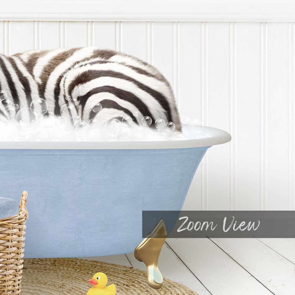 A zebra lying in a blue bathtub filled with bubbles, surrounded by a yellow rubber duck and a woven basket.