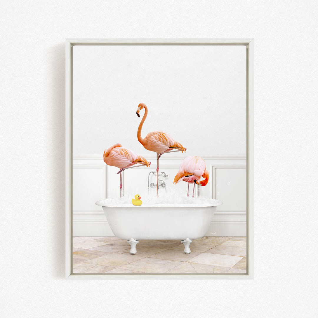 A framed image depicting three flamingos standing in a white bathtub filled with water, with a yellow rubber duck floating in the water.