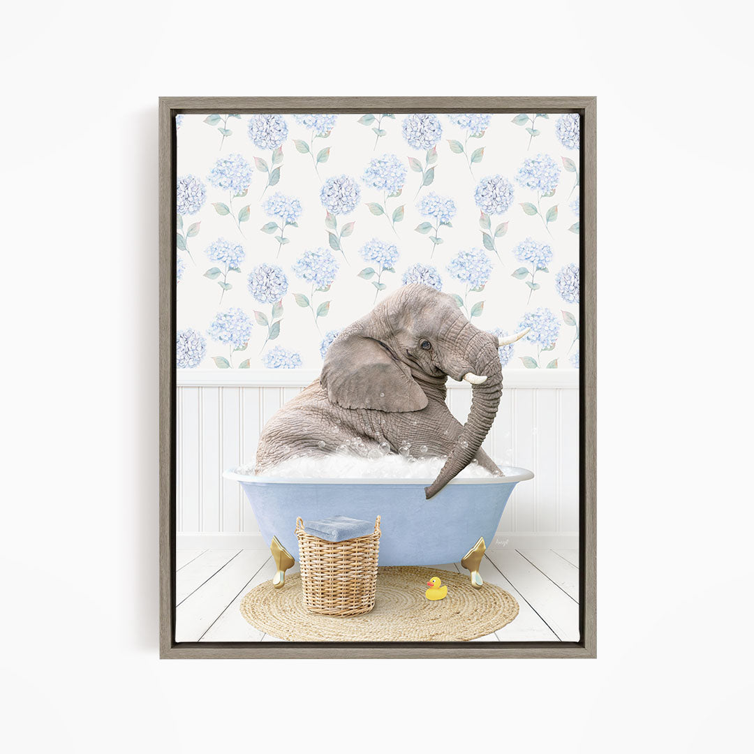 A gray elephant is sitting in a blue bathtub filled with water, surrounded by a wicker basket and yellow rubber ducks.