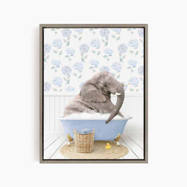 A gray elephant is sitting in a blue bathtub filled with water, surrounded by a wicker basket and yellow rubber ducks.
