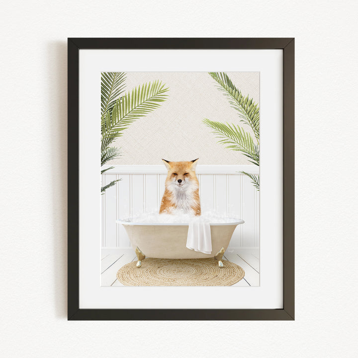 A framed image depicting a fox sitting in a bathtub filled with bubbles, surrounded by green palm leaves.