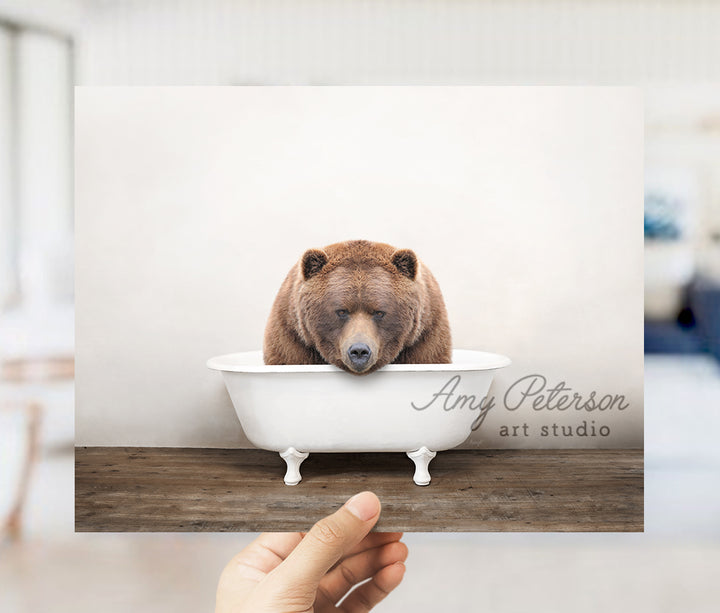 a person holding up a card with a bear in a bathtub