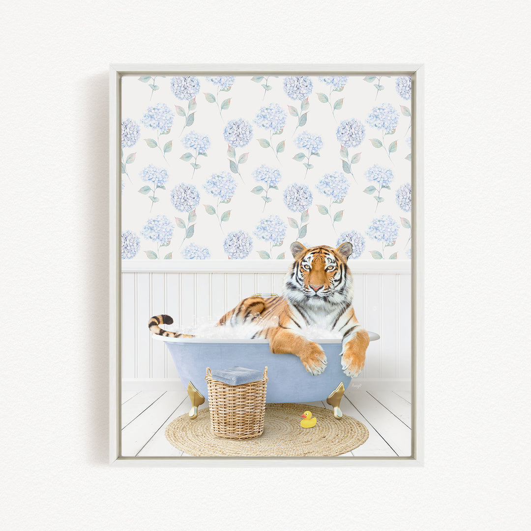 A tiger is sitting in a bathtub filled with water, surrounded by a blue and white floral patterned wallpaper and a basket of toys.