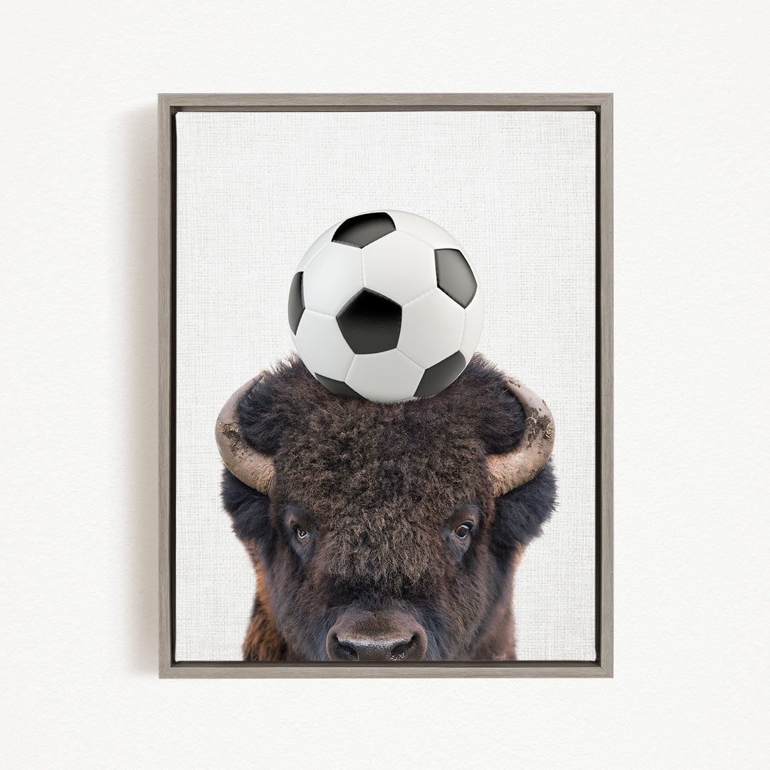 A buffalo with a soccer ball on its head.