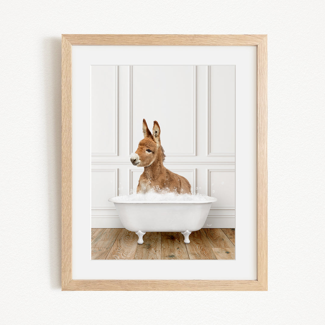 A donkey is sitting in a white bathtub filled with bubbles, looking at the camera.