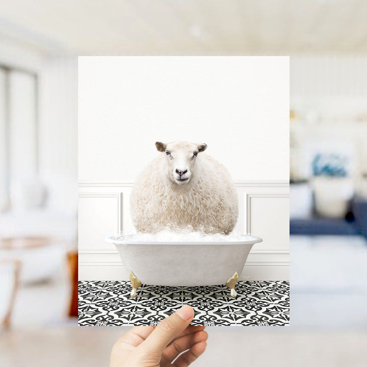 A fluffy white sheep sits in a white bathtub filled with bubbles, surrounded by a black and white patterned floor.