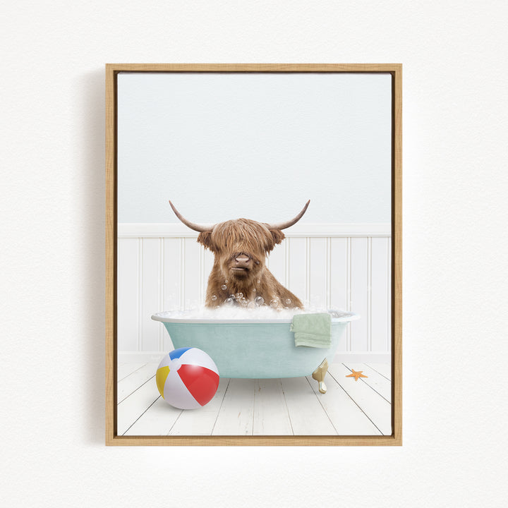 A brown cow with horns is sitting in a bathtub filled with water, surrounded by a beach ball and a towel.