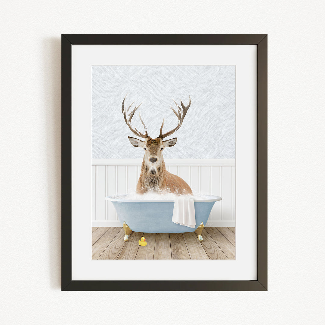 A deer with antlers is sitting in a bathtub filled with water, surrounded by rubber duckies.