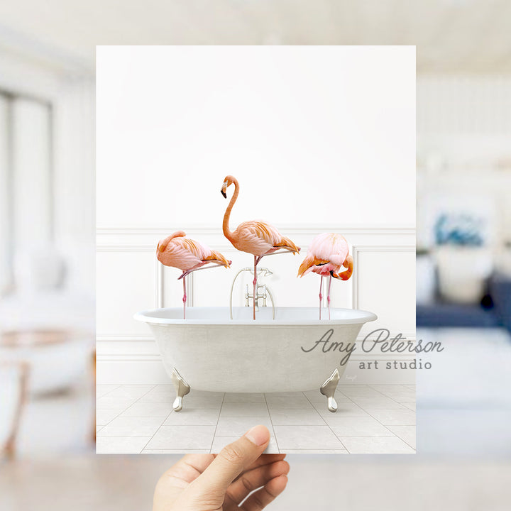 a person holding a card with three flamingos in a bathtub