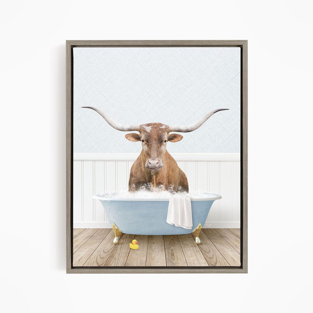 A brown bull with long horns is sitting in a blue bathtub filled with water, surrounded by yellow rubber ducks.