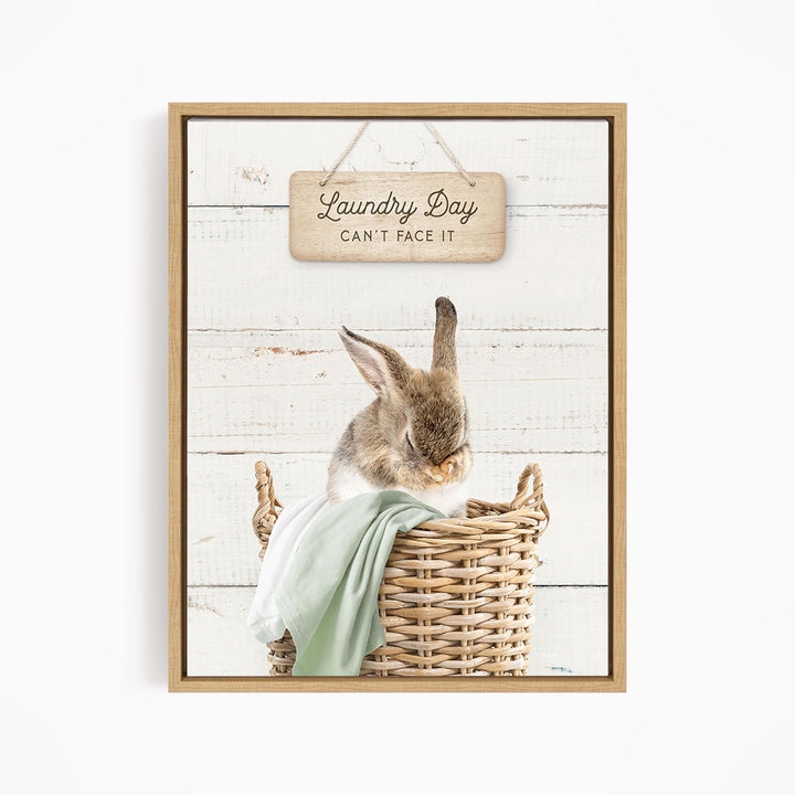 A cute rabbit sitting in a wicker basket, with a wooden sign above that says "Laundry Day Can't Face It".