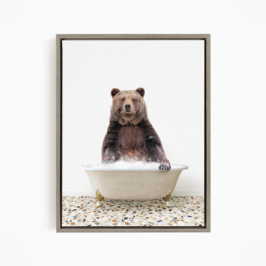 A brown bear sitting in a white bathtub filled with water, with its paws submerged in the water.