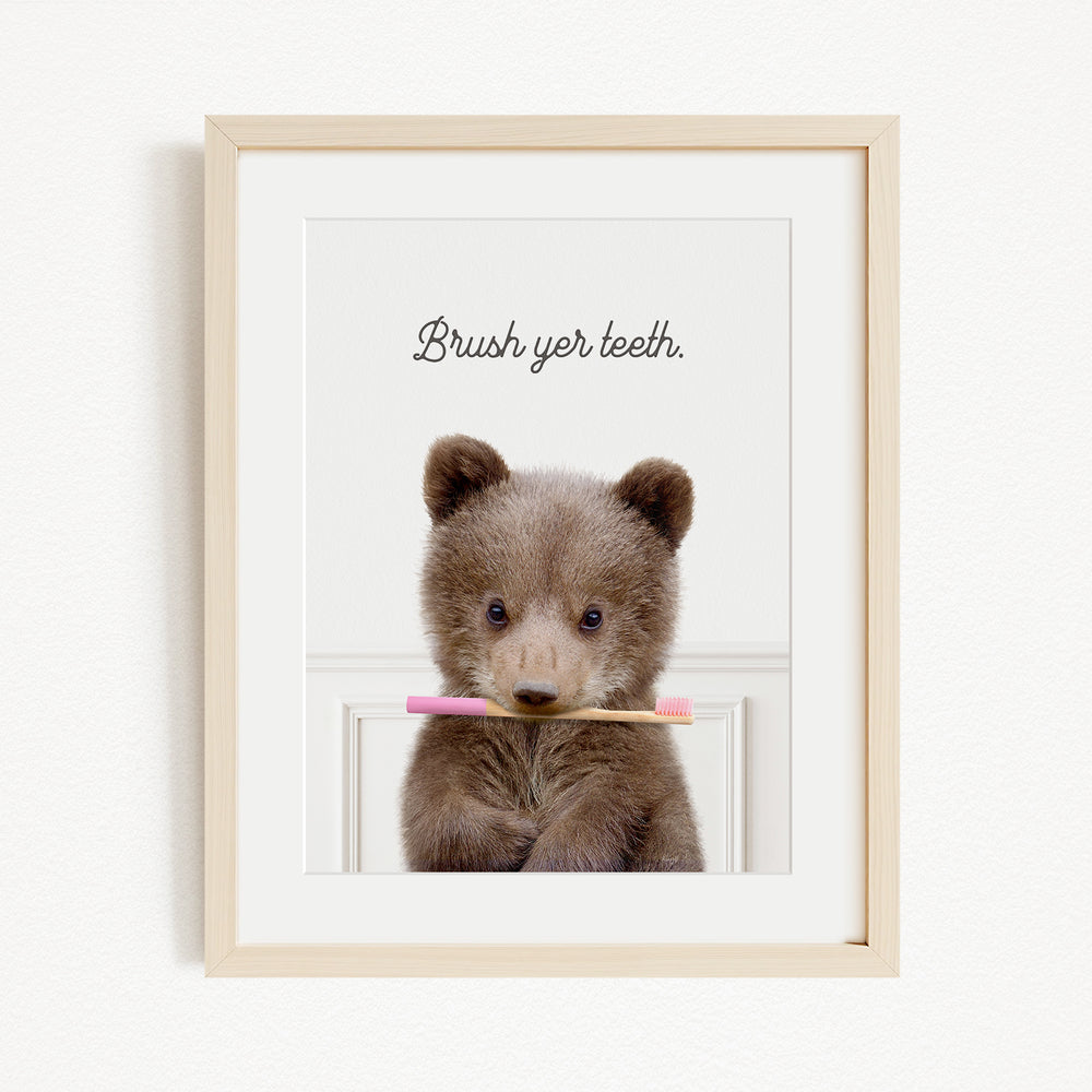 A cute brown bear holding a pink toothbrush in its mouth, with the text "Brush yer teeth" written above it.